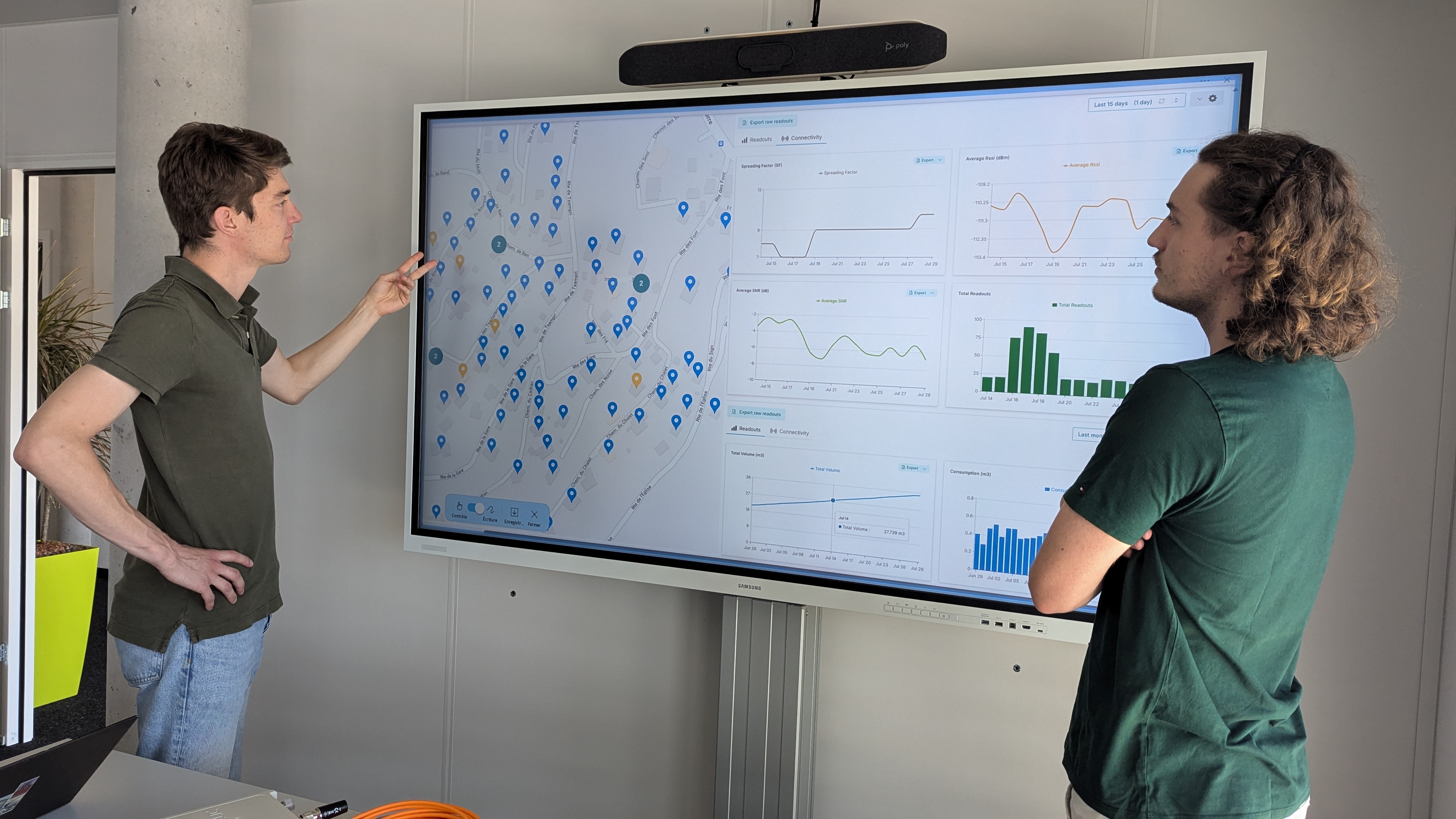 Zwei Personen betrachten ein Dashboard mit Netzkarte und Verbrauchsdiagrammen auf einem grossen Bildschirm.