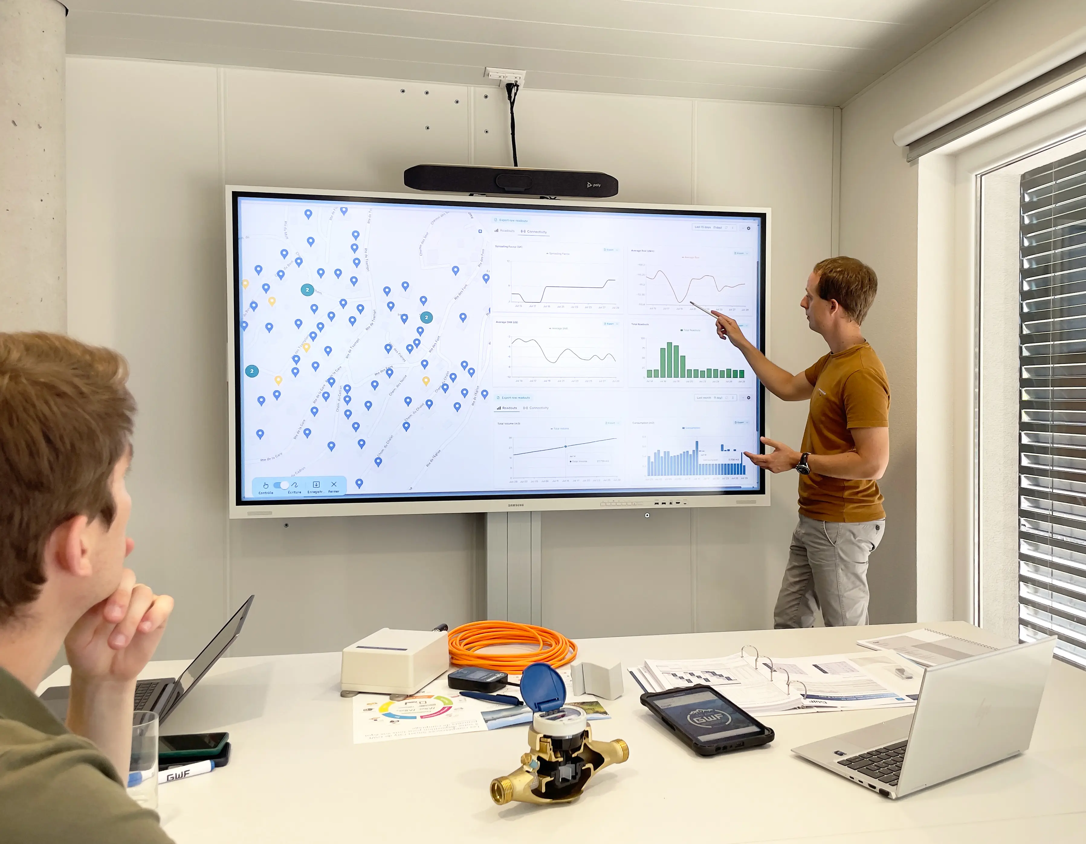 Referent erklärt ein Dashboard mit Netzkarte und Verbrauchsdiagrammen einer sitzenden Person.