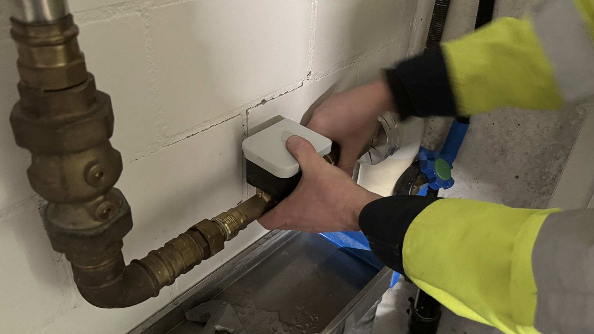 Zwei H$nde bauen Wasserzähler in eine bestehende Leitung ein.